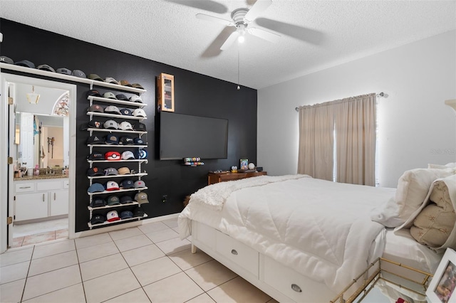 bedroom featuring ceiling fan, ensuite bath, a textured ceiling, and light tile patterned flooring