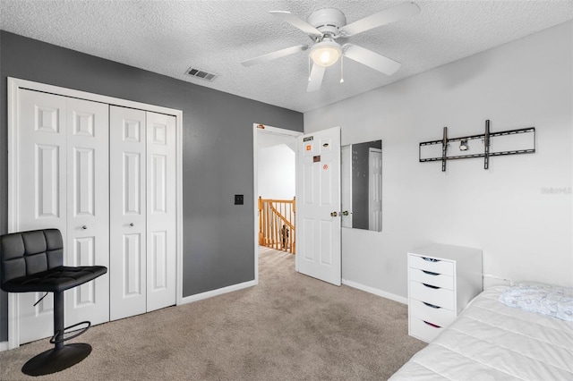 bedroom featuring light carpet, ceiling fan, a closet, and a textured ceiling