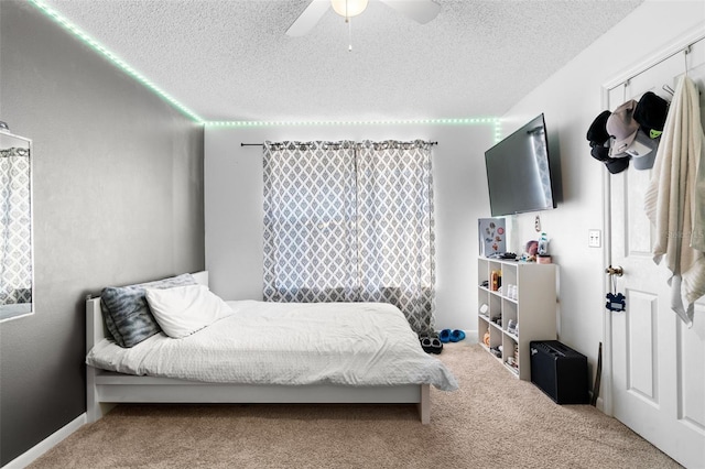 carpeted bedroom with ceiling fan and a textured ceiling