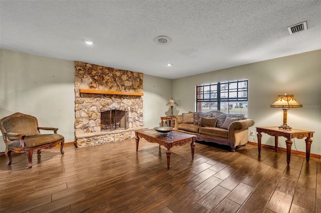 living room with a stone fireplace, dark wood-type flooring, and a textured ceiling