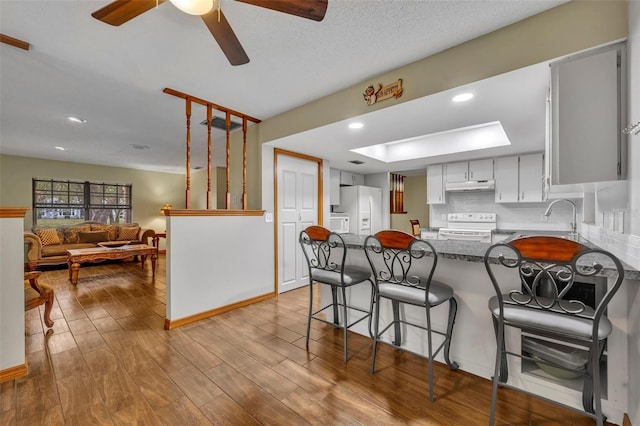 kitchen featuring sink, white cabinets, decorative backsplash, white appliances, and light hardwood / wood-style flooring