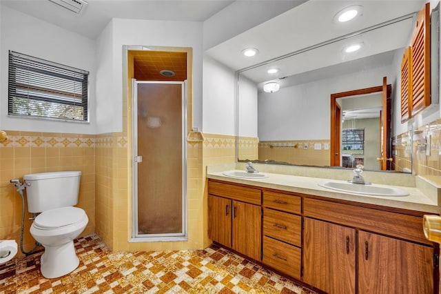 bathroom featuring a shower with door, vanity, tile walls, and toilet