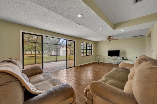 living room featuring hardwood / wood-style flooring, ceiling fan, and a textured ceiling