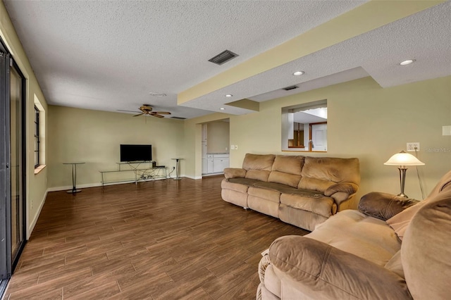 living room featuring ceiling fan, dark hardwood / wood-style floors, and a textured ceiling