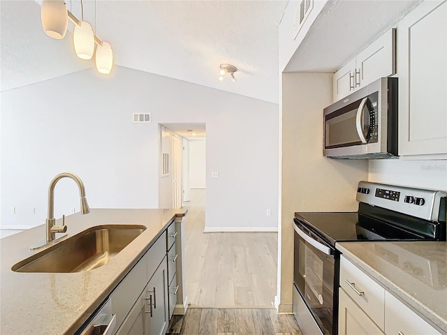 kitchen featuring sink, stainless steel appliances, light stone countertops, white cabinets, and decorative light fixtures