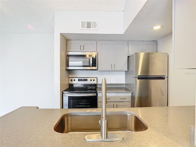 kitchen featuring light stone counters, sink, and appliances with stainless steel finishes