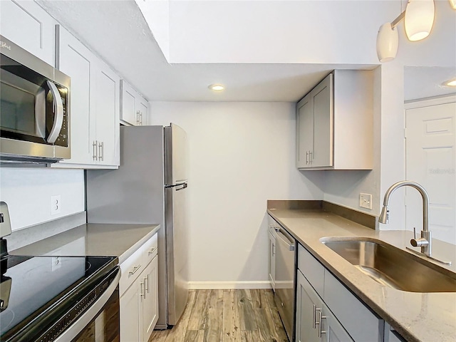 kitchen with sink, light hardwood / wood-style flooring, gray cabinets, pendant lighting, and stainless steel appliances