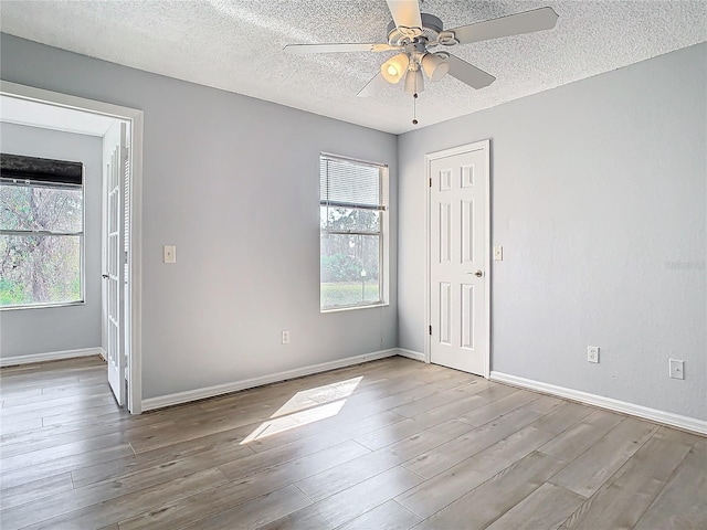 unfurnished room with ceiling fan, light hardwood / wood-style flooring, and a textured ceiling