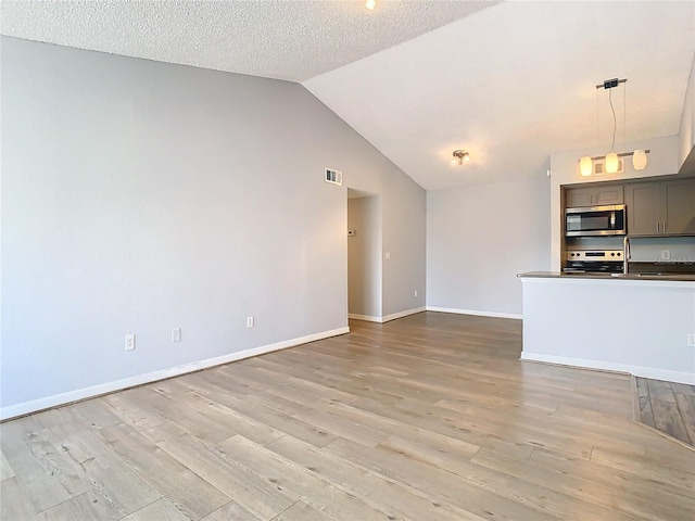 unfurnished living room with lofted ceiling, a textured ceiling, and light wood-type flooring