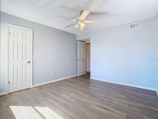 unfurnished room with ceiling fan, a textured ceiling, and light wood-type flooring