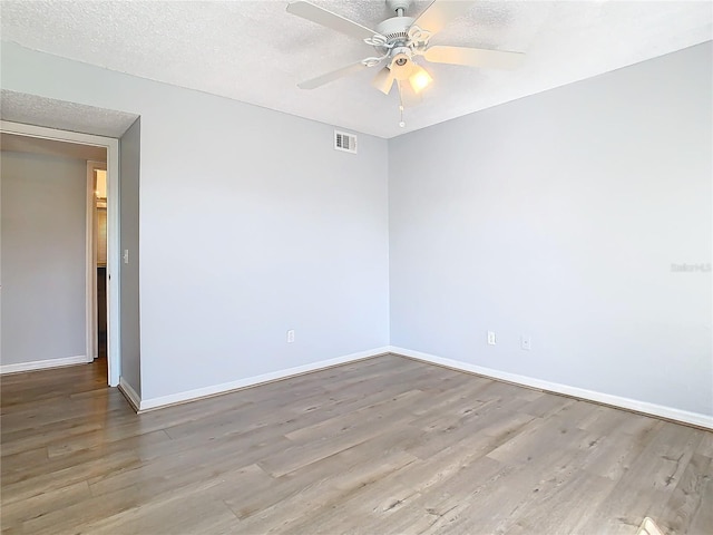 empty room with ceiling fan, light hardwood / wood-style flooring, and a textured ceiling