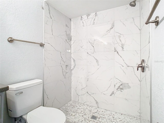 bathroom with tiled shower and toilet