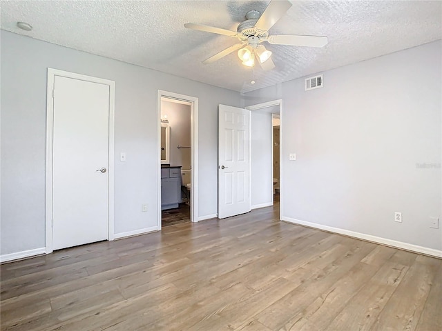 unfurnished bedroom featuring connected bathroom, ceiling fan, light hardwood / wood-style flooring, and a textured ceiling