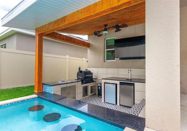 view of pool featuring a grill, an outdoor kitchen, sink, and ceiling fan