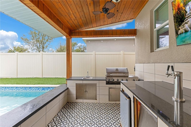 view of patio featuring an outdoor kitchen, a grill, sink, ceiling fan, and a fenced in pool