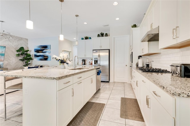 kitchen with pendant lighting, appliances with stainless steel finishes, sink, and a kitchen island with sink