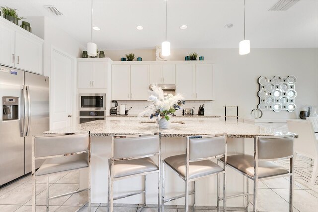 kitchen featuring a large island with sink, appliances with stainless steel finishes, white cabinets, and decorative light fixtures