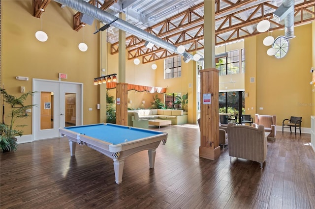 recreation room with hardwood / wood-style flooring, a towering ceiling, and french doors