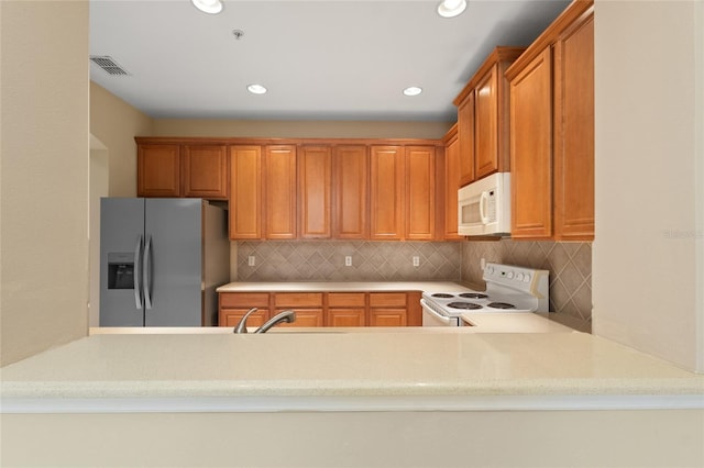980 Crestwood Commons Ave, Ocoee, FL 34761 - kitchen with white appliances, tasteful backsplash, recessed lighting, a peninsula, and light stone counters