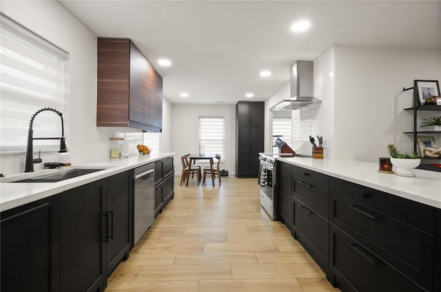 kitchen featuring sink, light hardwood / wood-style flooring, appliances with stainless steel finishes, decorative backsplash, and wall chimney range hood