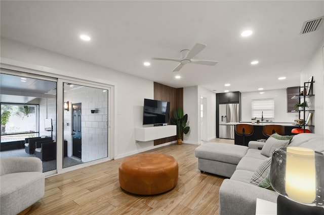 living room featuring sink, ceiling fan, and light hardwood / wood-style flooring