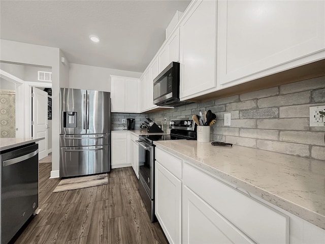 kitchen featuring appliances with stainless steel finishes, white cabinetry, backsplash, dark hardwood / wood-style floors, and light stone countertops