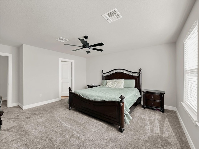 carpeted bedroom featuring ceiling fan, multiple windows, and a textured ceiling