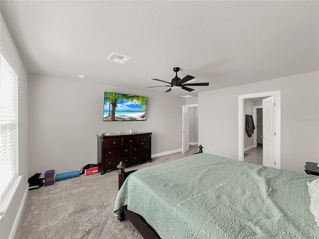 bedroom featuring ceiling fan, light colored carpet, multiple windows, and a textured ceiling