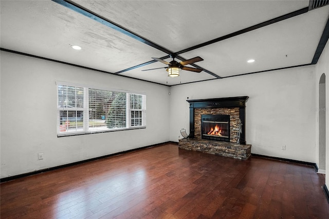 unfurnished living room with a stone fireplace, dark hardwood / wood-style floors, and ceiling fan