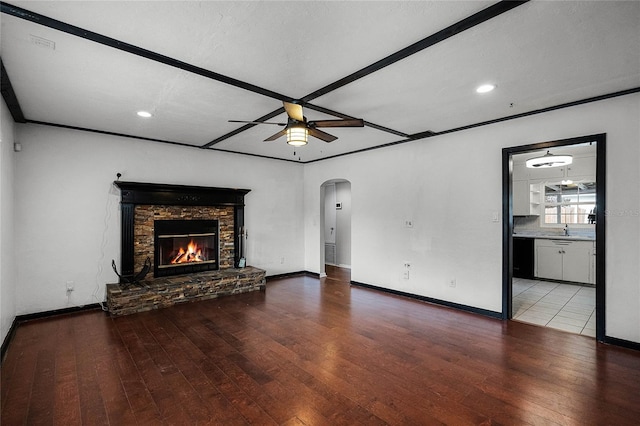 unfurnished living room with sink, a stone fireplace, light hardwood / wood-style floors, and ceiling fan