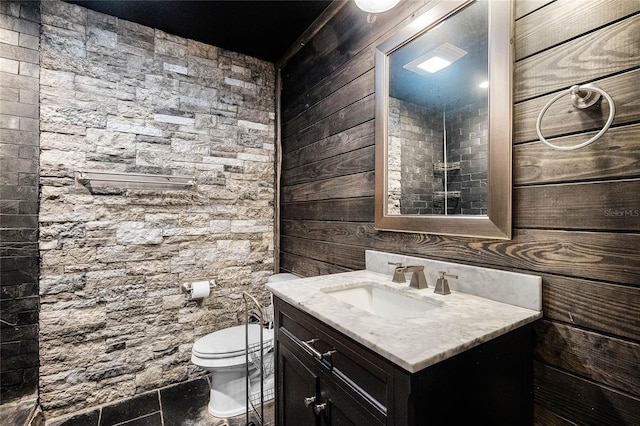 bathroom with vanity, toilet, and wood walls