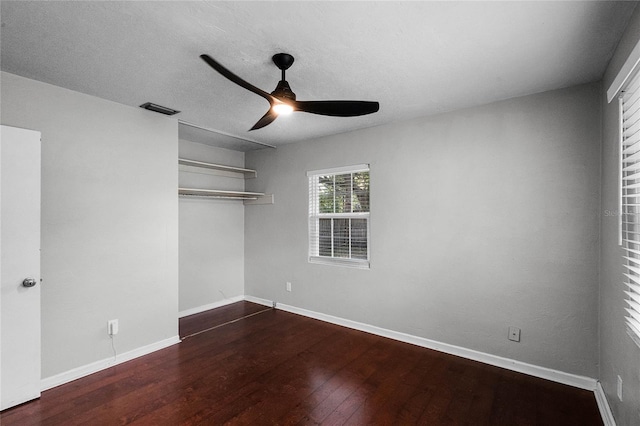 unfurnished bedroom with a closet, a textured ceiling, dark hardwood / wood-style floors, and ceiling fan