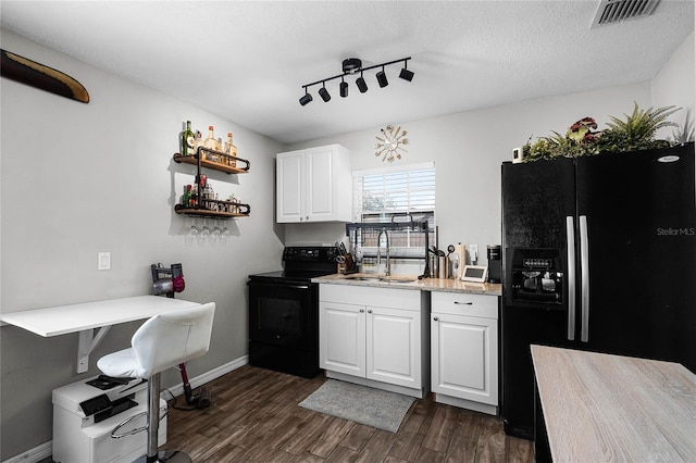 kitchen featuring dark hardwood / wood-style floors, sink, white cabinets, black appliances, and a textured ceiling