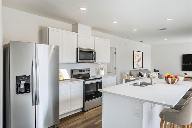 kitchen featuring stainless steel appliances, an island with sink, sink, and white cabinetry