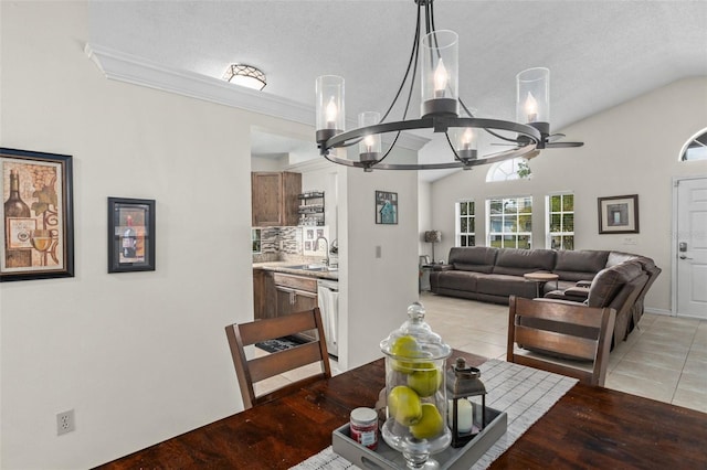 tiled dining area featuring sink, crown molding, an inviting chandelier, a textured ceiling, and vaulted ceiling