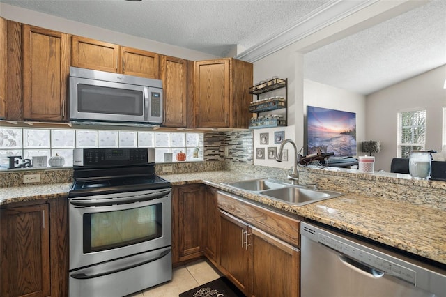 kitchen featuring sink, decorative backsplash, light tile patterned floors, stainless steel appliances, and a textured ceiling