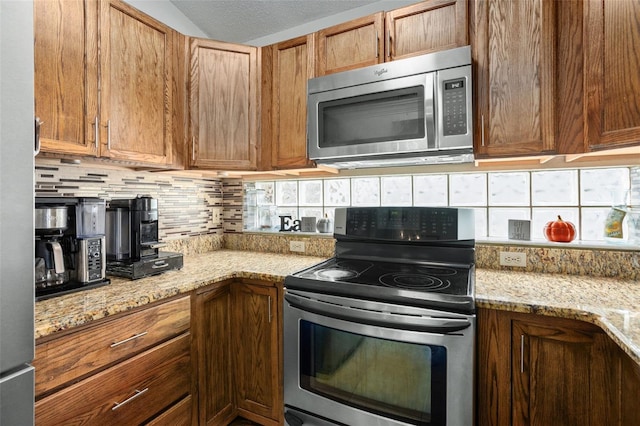 kitchen with backsplash, a wealth of natural light, stainless steel appliances, and light stone countertops