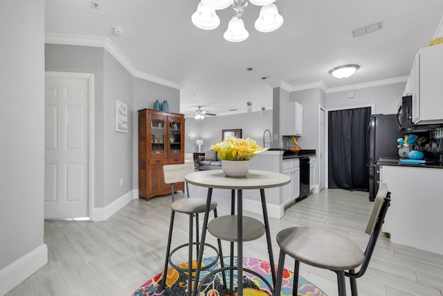 kitchen with ceiling fan with notable chandelier, white cabinets, ornamental molding, black appliances, and light hardwood / wood-style flooring