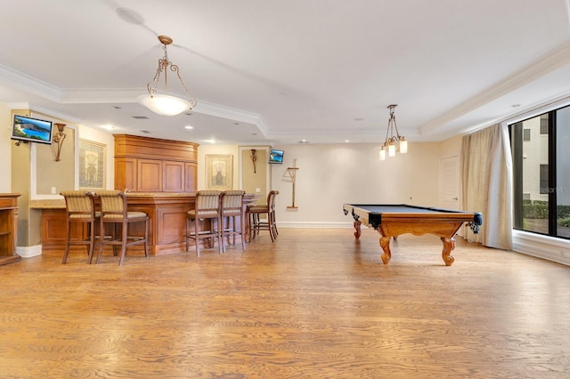 rec room featuring bar, a tray ceiling, light hardwood / wood-style flooring, and crown molding