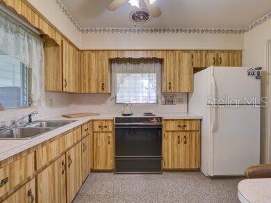 kitchen with white refrigerator, range with electric stovetop, sink, and ceiling fan