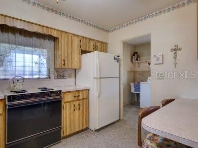 kitchen featuring black / electric stove and white fridge