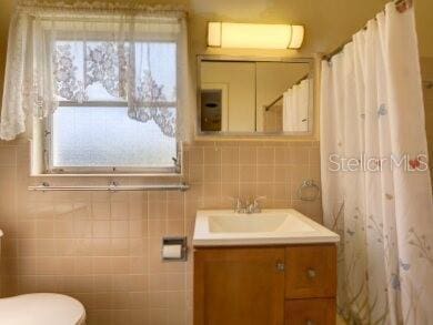 bathroom with vanity, tile walls, and toilet