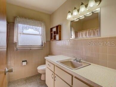 bathroom with vanity, toilet, and tile walls