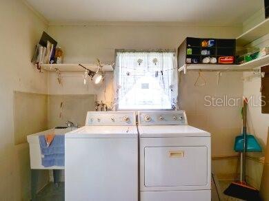 clothes washing area with washing machine and dryer and sink