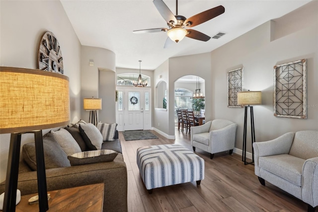 living room featuring dark wood-type flooring and ceiling fan with notable chandelier