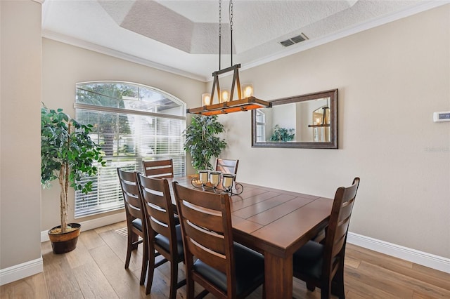 dining area with ornamental molding, hardwood / wood-style floors, and a textured ceiling