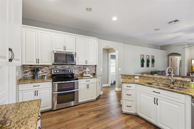 kitchen with sink, tasteful backsplash, dark stone countertops, stainless steel appliances, and white cabinets