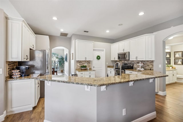 kitchen featuring appliances with stainless steel finishes, a kitchen island with sink, and white cabinets