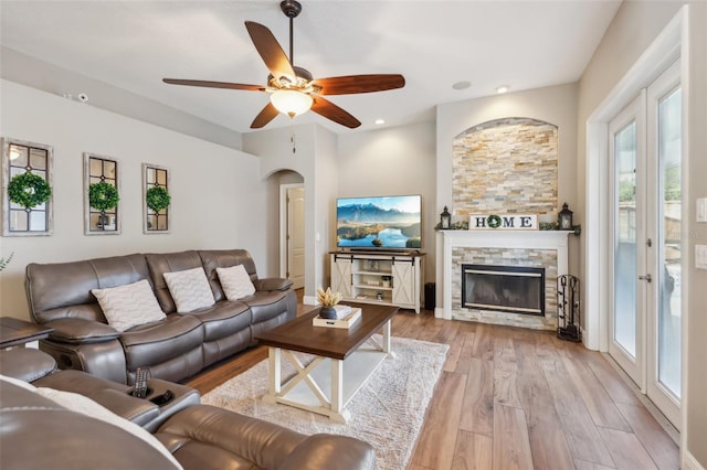 living room featuring a fireplace, light hardwood / wood-style flooring, and ceiling fan