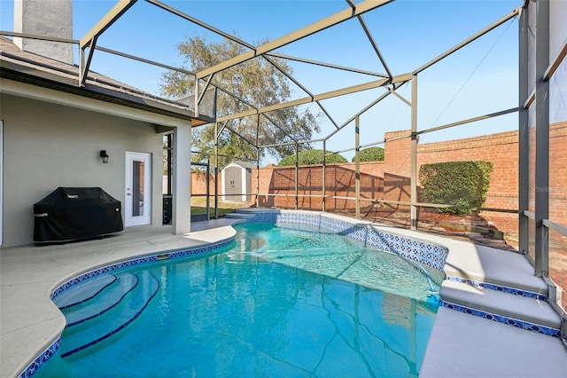 view of swimming pool featuring a grill, a lanai, a patio area, and a shed